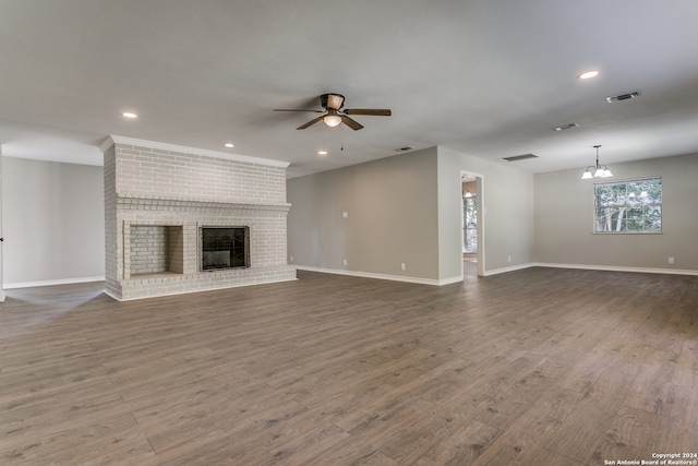 unfurnished living room featuring a fireplace, ceiling fan with notable chandelier, and hardwood / wood-style flooring