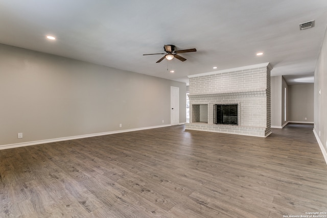 unfurnished living room featuring dark hardwood / wood-style floors, ceiling fan, and a brick fireplace