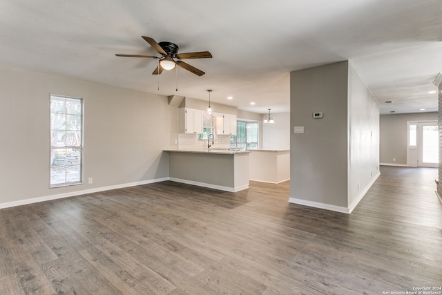 unfurnished living room with ceiling fan, plenty of natural light, wood-type flooring, and sink