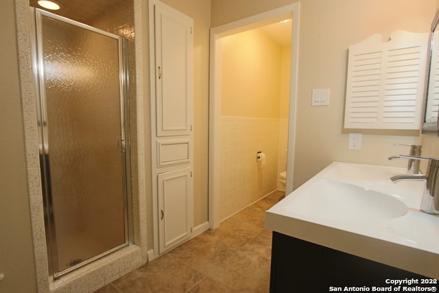 bathroom with tile patterned flooring, vanity, toilet, and a shower with shower door