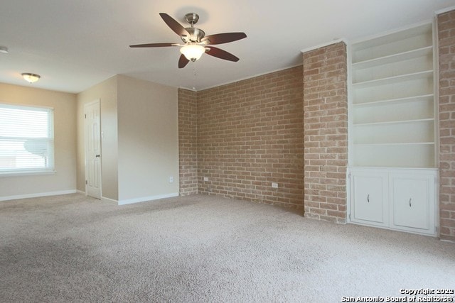 empty room with light colored carpet, brick wall, and ceiling fan