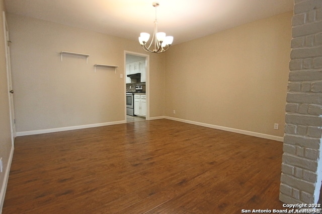 unfurnished living room with a chandelier and dark hardwood / wood-style flooring