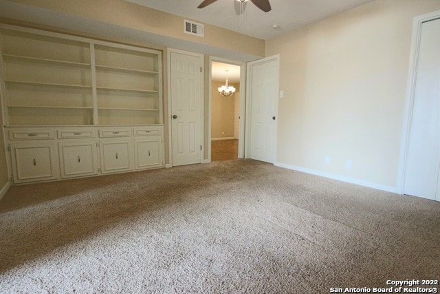 unfurnished bedroom with ceiling fan with notable chandelier and carpet