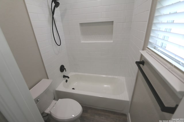 bathroom featuring hardwood / wood-style flooring, tiled shower / bath combo, and toilet