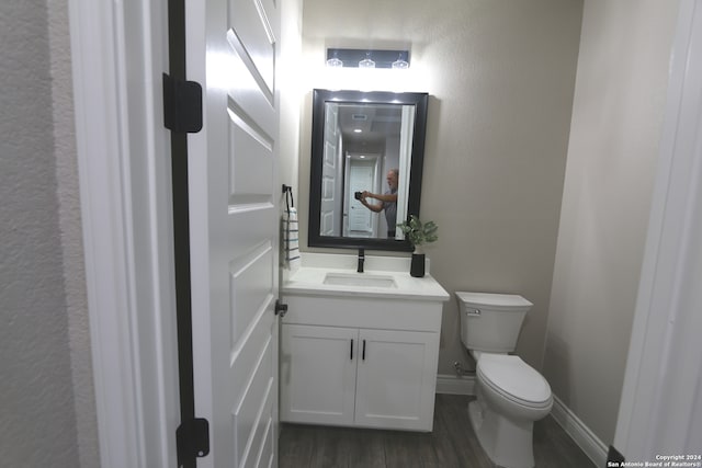 bathroom with hardwood / wood-style floors, vanity, and toilet