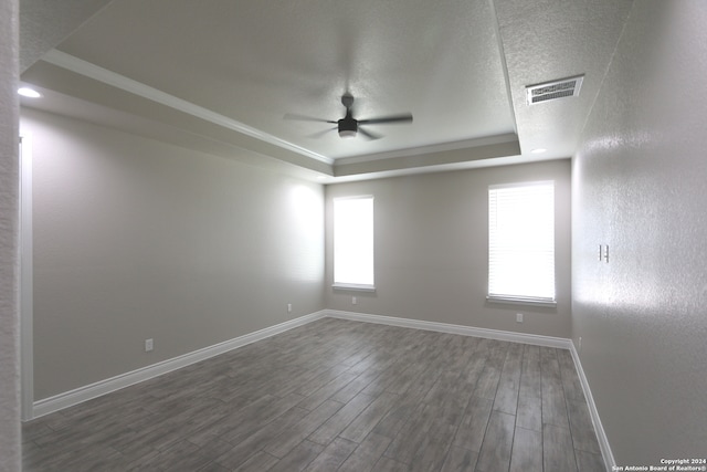 unfurnished room with a textured ceiling, dark hardwood / wood-style flooring, a raised ceiling, and ceiling fan