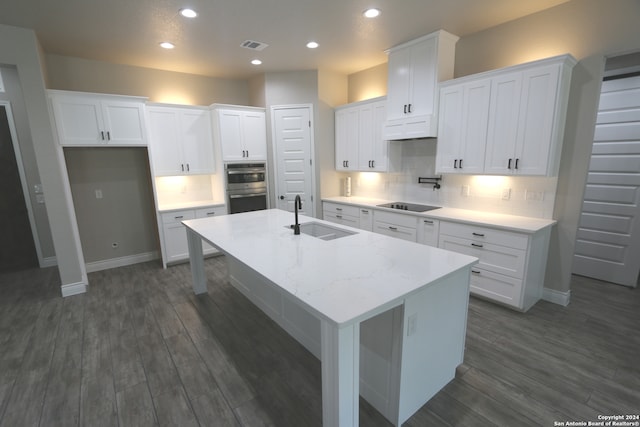 kitchen featuring white cabinets, a center island with sink, sink, and dark wood-type flooring