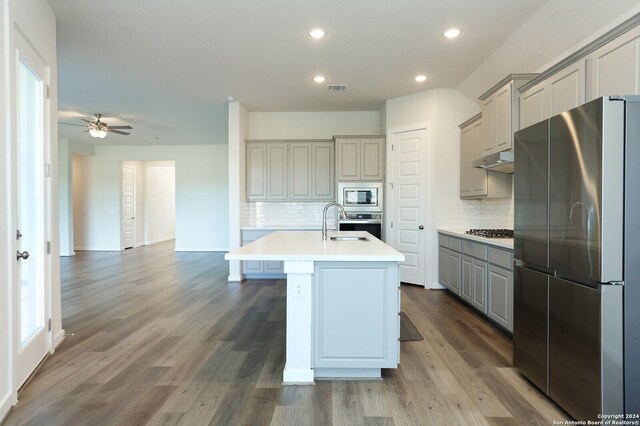 11514 Hollering Pass, Schertz, TX 78154 - kitchen with appliances with stainless steel finishes, gray cabinetry, tasteful backsplash, recessed lighting, and a kitchen island with sink