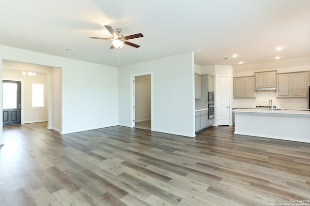 11514 Hollering Pass, Schertz, TX 78154 - unfurnished living room with ceiling fan, recessed lighting, wood finished floors, baseboards, and a sink