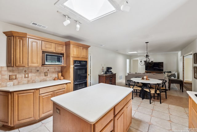 kitchen featuring backsplash, black double oven, stainless steel microwave, a kitchen island, and hanging light fixtures