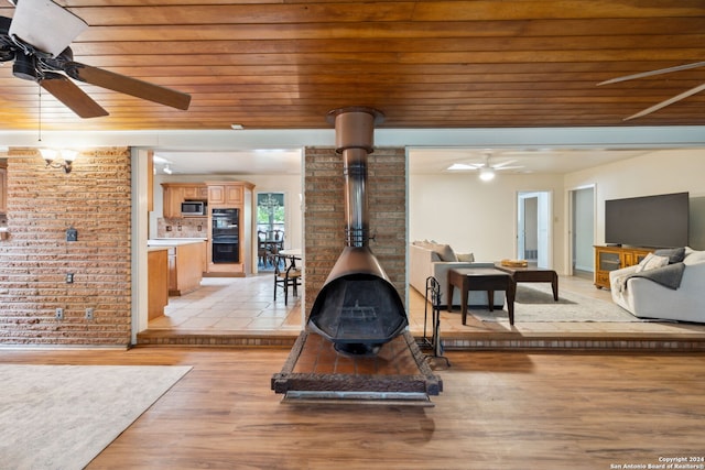 living room featuring wooden ceiling, a wood stove, brick wall, and light hardwood / wood-style flooring