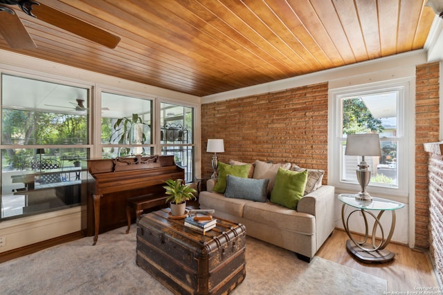 living room with light hardwood / wood-style flooring, a healthy amount of sunlight, and brick wall