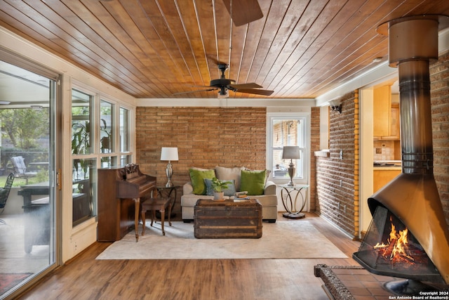 sunroom featuring ceiling fan, wood ceiling, and a wood stove