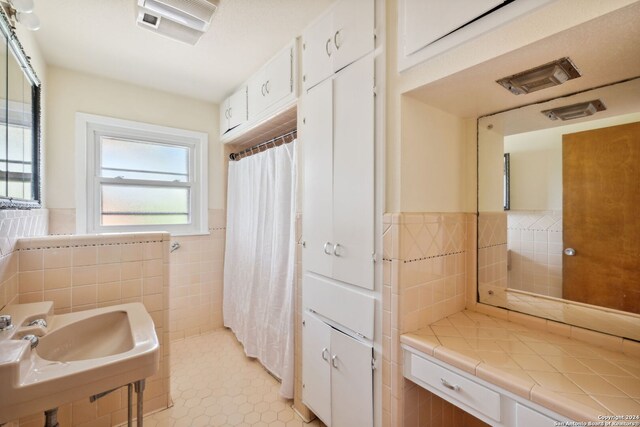 bathroom featuring tile patterned floors, sink, and tile walls