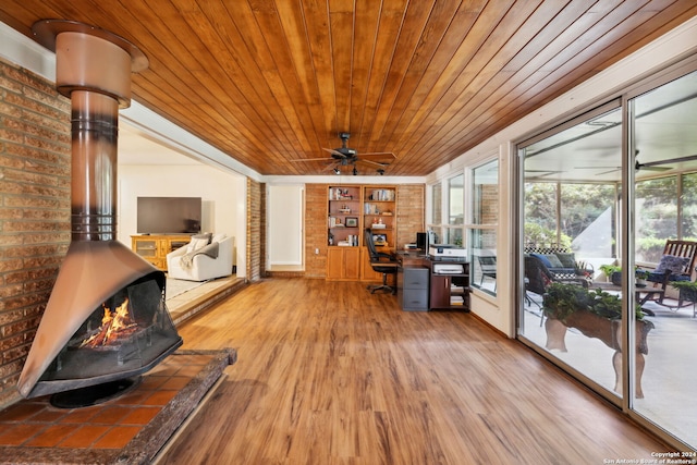 interior space with hardwood / wood-style floors, wooden ceiling, a wood stove, built in shelves, and brick wall