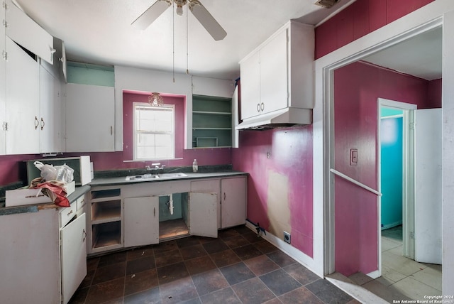 522 Ave B, Poteet, TX 78065 - kitchen with a sink, a ceiling fan, white cabinetry, baseboards, and under cabinet range hood