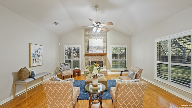 living room with a fireplace, light hardwood / wood-style flooring, ceiling fan, and vaulted ceiling