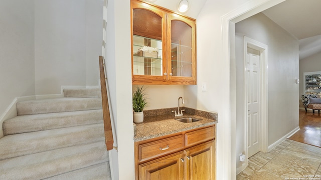 bar featuring light hardwood / wood-style flooring, sink, and light stone counters