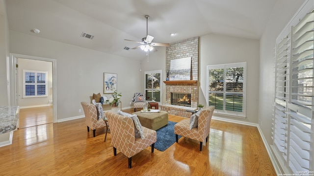 living room with a fireplace, light hardwood / wood-style floors, ceiling fan, and vaulted ceiling