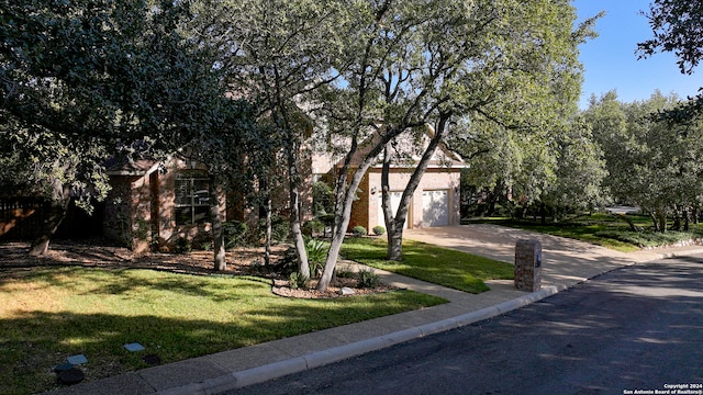 view of property hidden behind natural elements with a garage and a front yard