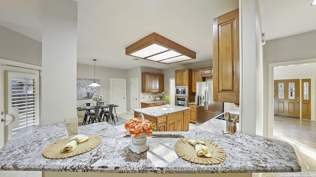 kitchen featuring light stone counters, a center island, tasteful backsplash, appliances with stainless steel finishes, and decorative light fixtures