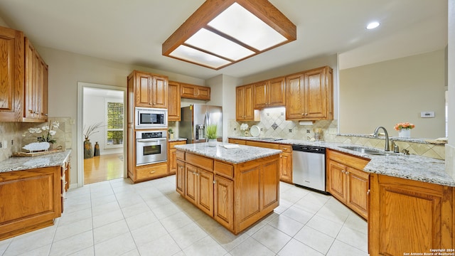 kitchen with light stone countertops, sink, backsplash, and stainless steel appliances