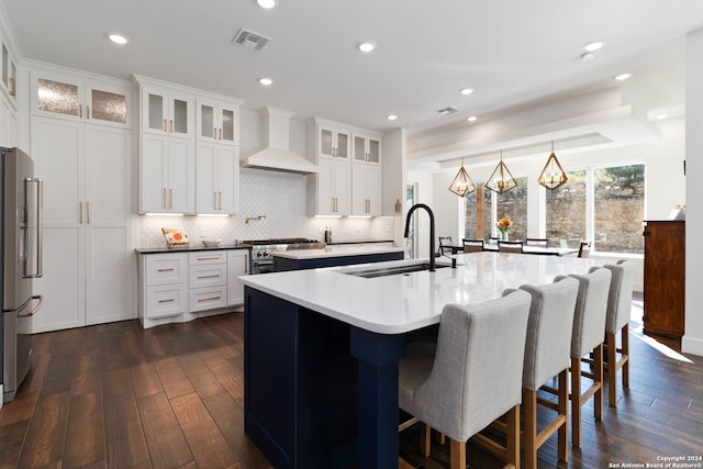 kitchen featuring a center island with sink, appliances with stainless steel finishes, sink, dark wood-type flooring, and custom exhaust hood