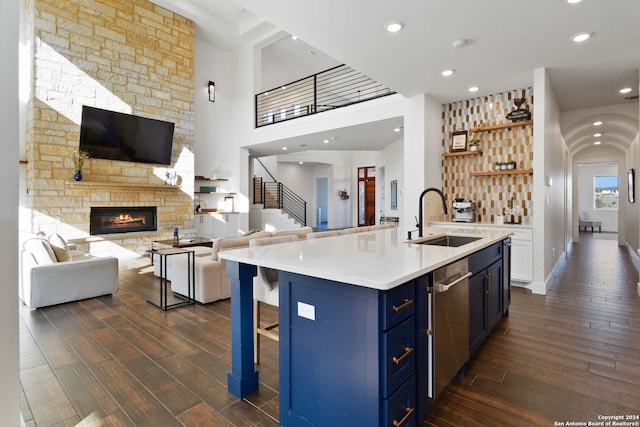 kitchen with sink, a kitchen breakfast bar, an island with sink, blue cabinetry, and dark hardwood / wood-style flooring