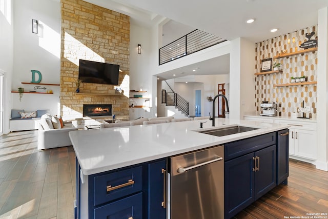 kitchen featuring dark wood-type flooring, blue cabinetry, sink, and an island with sink