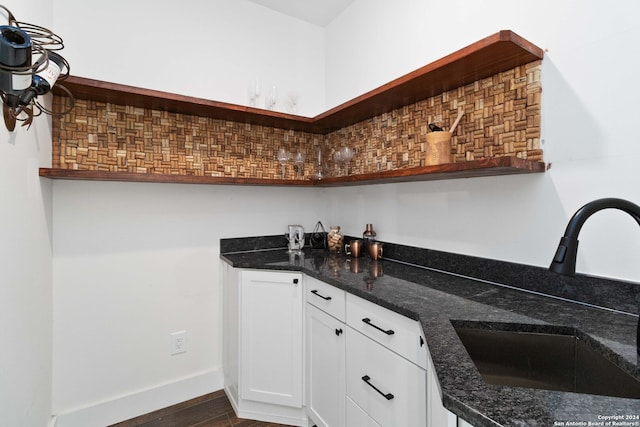 bar with white cabinets, dark stone counters, sink, and dark wood-type flooring