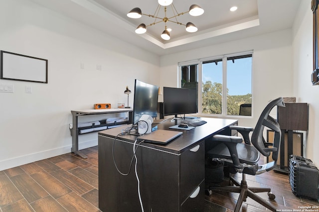 home office featuring dark wood-type flooring, a chandelier, and a tray ceiling