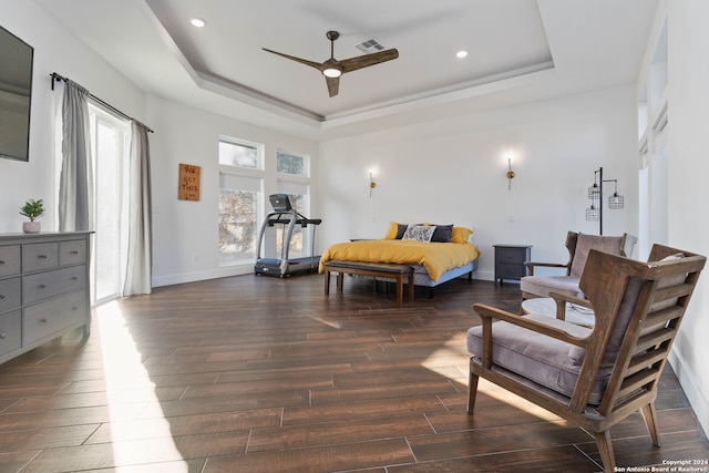 bedroom featuring dark hardwood / wood-style flooring, ceiling fan, and a raised ceiling