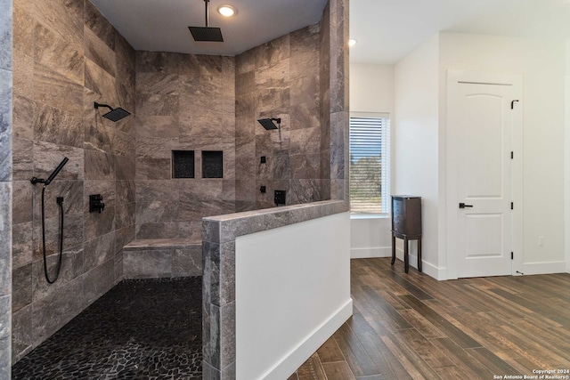 bathroom with tiled shower and wood-type flooring