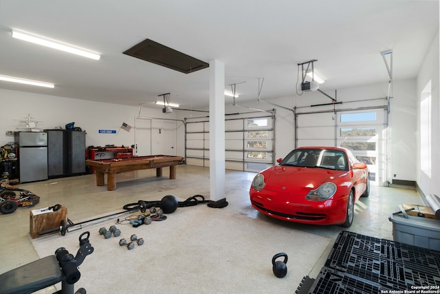 garage with a garage door opener and stainless steel refrigerator