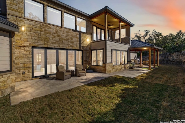 back house at dusk featuring a patio, a yard, a gazebo, and a balcony