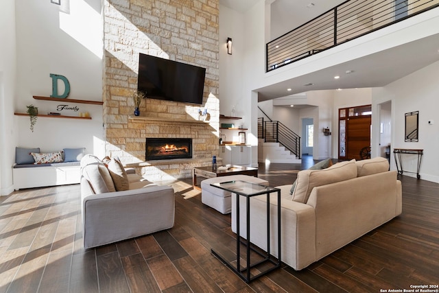 living room featuring a towering ceiling, dark hardwood / wood-style floors, and a stone fireplace