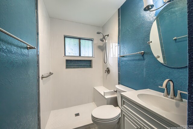 bathroom with tiled shower, toilet, and vanity