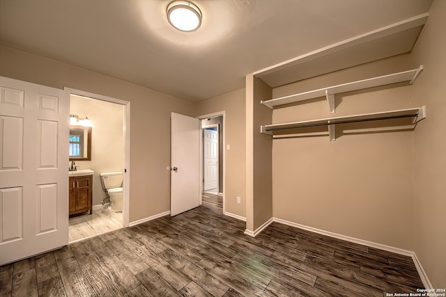 unfurnished bedroom with dark hardwood / wood-style flooring, sink, ensuite bath, and a closet