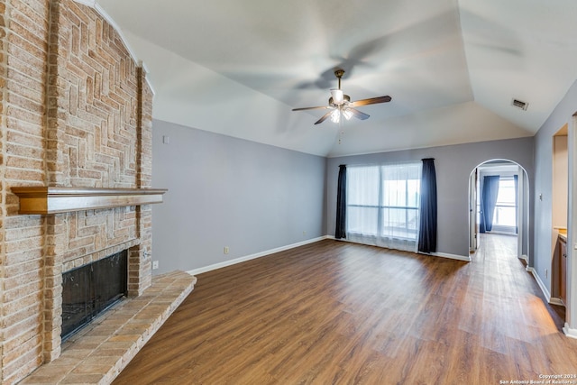 10311 Grand Cir, San Antonio, TX 78239 - unfurnished living room with a ceiling fan, arched walkways, vaulted ceiling, a brick fireplace, and wood finished floors