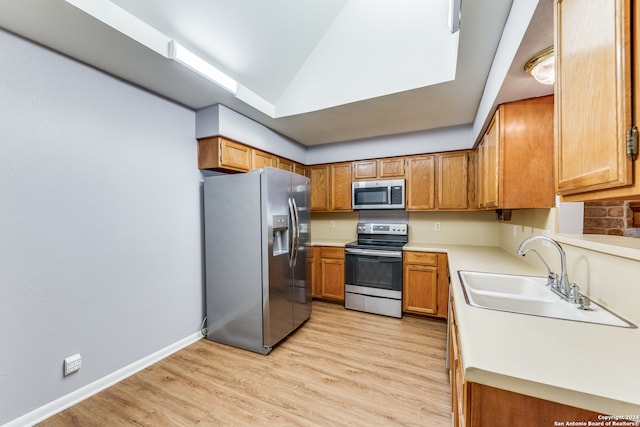 kitchen with light wood-type flooring, lofted ceiling, sink, and stainless steel appliances