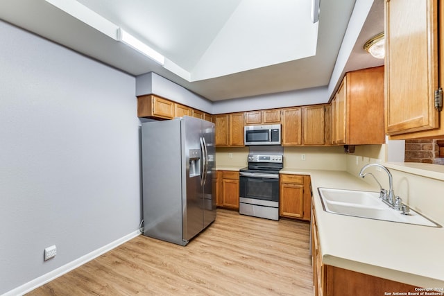 10311 Grand Cir, San Antonio, TX 78239 - kitchen featuring appliances with stainless steel finishes, a sink, brown cabinets, and vaulted ceiling