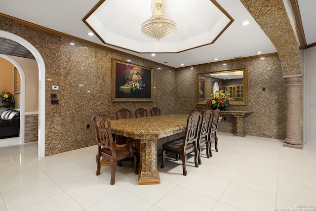 dining room with ornamental molding, light tile patterned floors, ornate columns, an inviting chandelier, and a tray ceiling