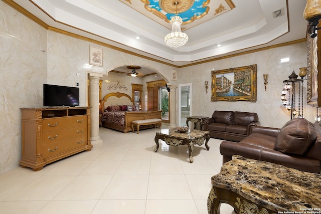 living room featuring ornamental molding, ceiling fan, light tile patterned floors, a tray ceiling, and decorative columns