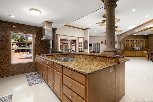 kitchen featuring dark stone countertops, sink, crown molding, and decorative columns