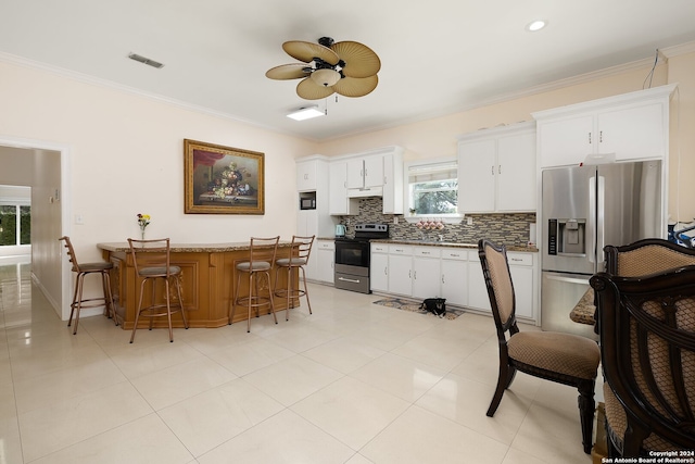 kitchen with plenty of natural light, appliances with stainless steel finishes, a breakfast bar area, and white cabinets