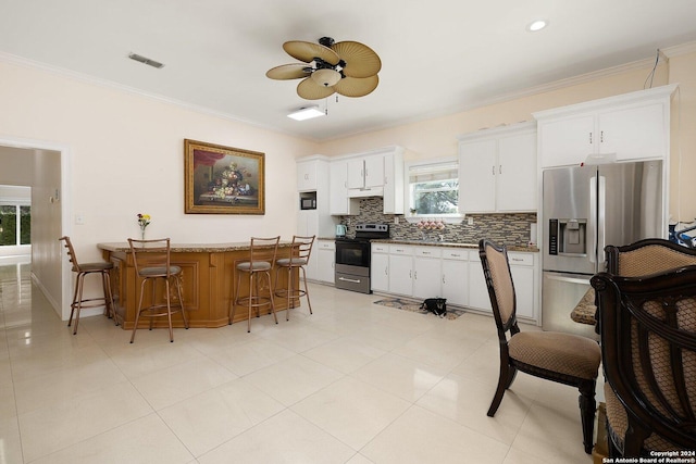 2301 Tanglewood, Weslaco, TX 78596 - kitchen with appliances with stainless steel finishes, a ceiling fan, backsplash, crown molding, and a kitchen bar
