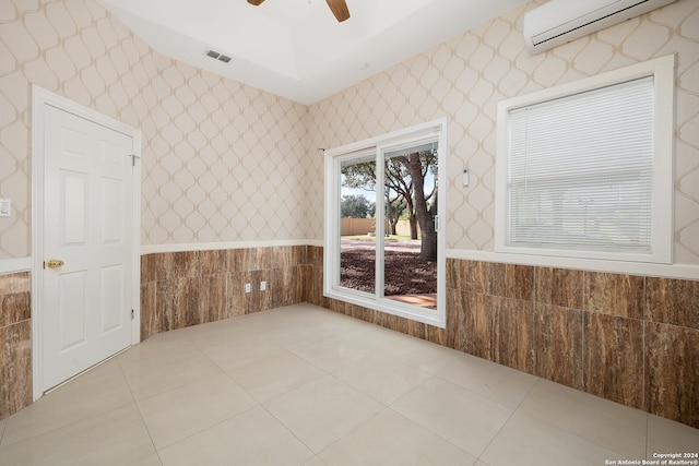 unfurnished room with tile walls, a wall unit AC, ceiling fan, and light tile patterned floors