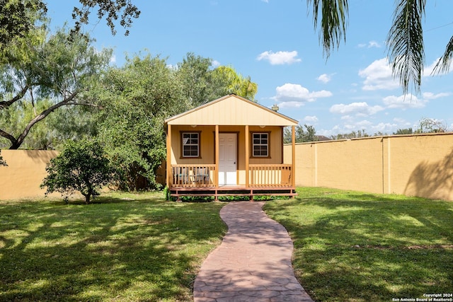 view of front facade with a front lawn, an outdoor structure, and a wooden deck