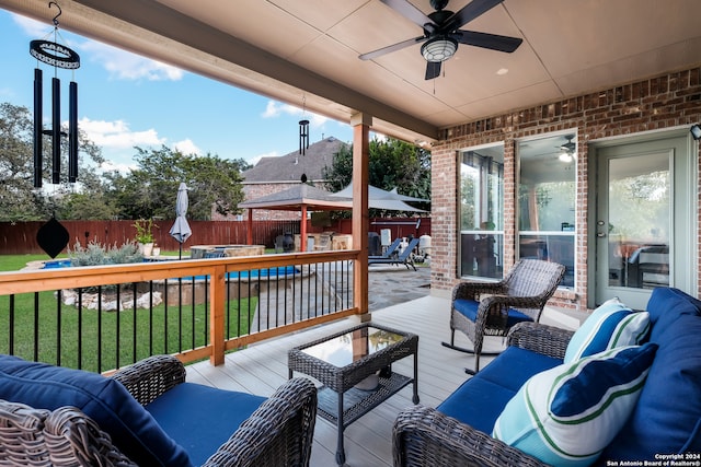 deck with outdoor lounge area, ceiling fan, and a yard