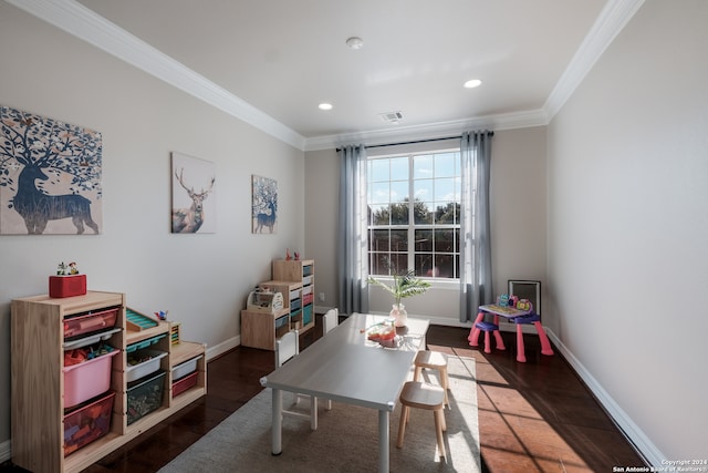 recreation room with ornamental molding and dark hardwood / wood-style floors